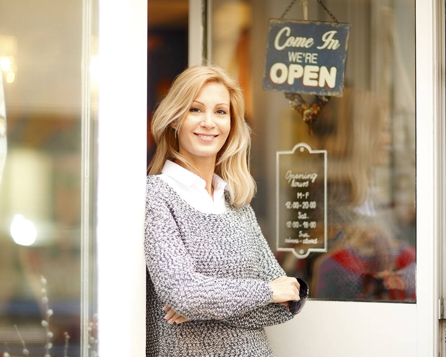 business owener standing by Open sign on door